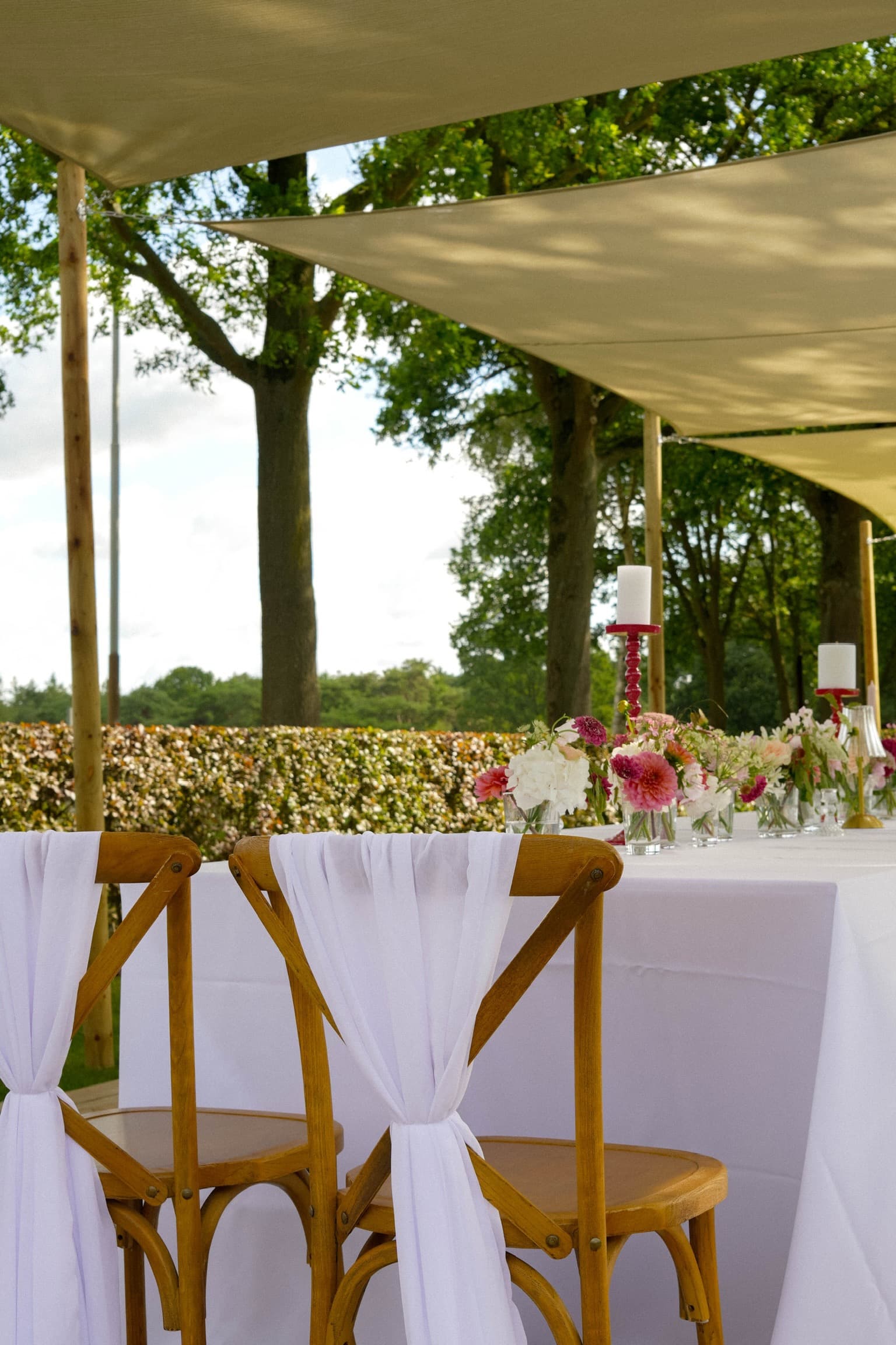 Lumae event styling — gedekte tafel met gedrapeerde stoelen in de buitenlucht